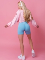 Nowoczesny model damskiej, uciętej bluzy z szerokimi rękawami i rozcięciem na ramieniu w kolorze różowym