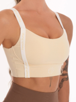 Bež sportski grudnjak s bijelim naramenicama i bež natpisima Peach Pump